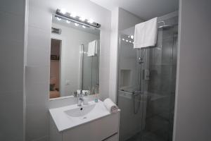 uma casa de banho branca com um lavatório e um chuveiro em DreamsApt Placentines em Sevilha