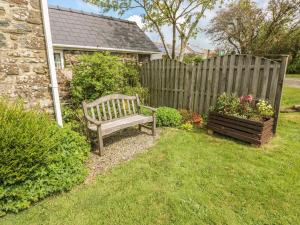 un banco de madera sentado en un patio junto a una valla en Eynons Cottage, en Roch