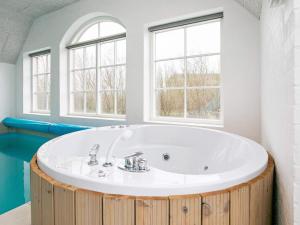 uma casa de banho com banheira e 2 janelas em 16 person holiday home in Ulfborg em Ulfborg