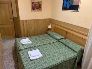 Dos camas en una habitación pequeña con toallas blancas. en Hostal Juan XXIII, en San Sebastián de los Reyes