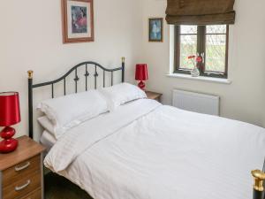 a bedroom with a bed with white sheets and red lamps at Marina View in Burry Port