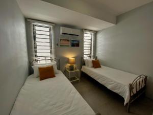 two beds in a room with two windows at Under The Tropics in Tamarin