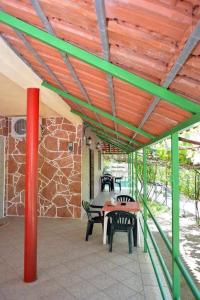 a patio with a table and chairs under a wooden ceiling at Romeo’s Guest House 2 in Piqeras
