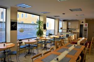 a restaurant with wooden tables and chairs and windows at Economy Hotel Kronach in Kronach