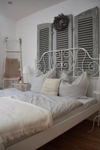 een witte slaapkamer met een bed met kussens bij Gemütliche Ferienwohnung in Edesheim an der Weinstraße in Edesheim