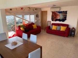 a living room with two red couches and a table at Apartamento en primera línea de mar, 8 personas in Platja d'Aro