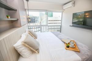 1 dormitorio con cama blanca y ventana grande en Trendy Host Black - San Isidro, en Lima