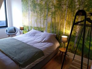 1 dormitorio con 1 cama con un mural de árboles en B&B Tantine, en Retie