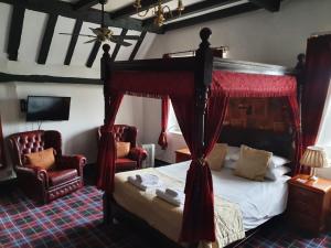 a bedroom with a canopy bed and two chairs at Old Court Hotel & Apartments in Symonds Yat