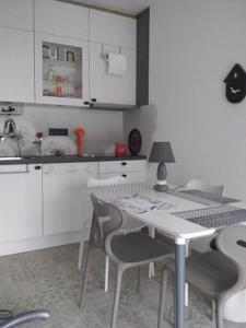a kitchen with white cabinets and a table and chairs at Aosta in Koksijde