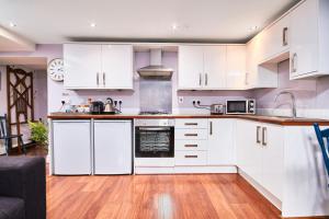 cocina con armarios blancos y suelo de madera en Newcastle Treasure - sleeps 4, en Newcastle