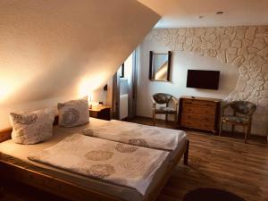 a bedroom with a bed and two chairs and a television at Ferienwohnung Reichelt in Neuwinsen
