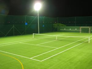 a tennis court lit up at night with a light at Quinta Do Molinu in Lourinhã