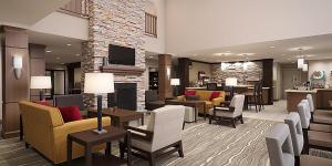 Staybridge Suites - Sioux Falls Southwest, an IHG Hotel في شلالات سيوكس: لوبي الفندق مع كراسي وطاولات ومدفأة