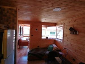 Habitación con cama en una habitación de madera con ventanas en Cabaña sol y luna, en El Quisco
