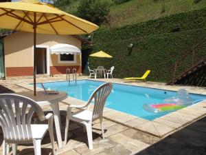 een zwembad met een tafel en stoelen en een parasol bij Pousada Stohler Haus in Penedo