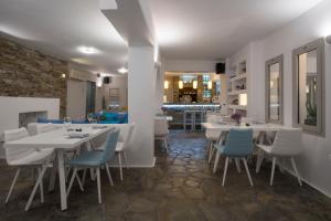 a dining room with white tables and blue chairs at Kanale's Rooms & Suites in Naousa