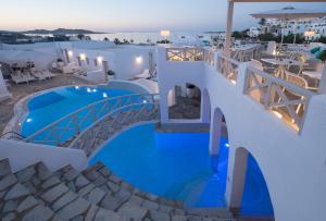 a resort with a blue pool and tables and chairs at Kanale's Rooms & Suites in Naousa