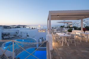 a restaurant with white tables and chairs on a roof at Kanale's Rooms & Suites in Naousa