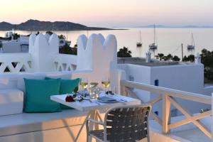 a table with wine glasses on a balcony with a view of the ocean at Kanale's Rooms & Suites in Naousa