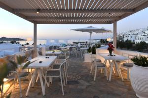 a restaurant with tables and chairs and an umbrella at Kanale's Rooms & Suites in Naousa
