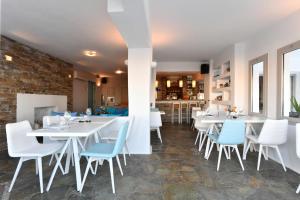 a restaurant with white tables and blue chairs at Kanale's Rooms & Suites in Naousa