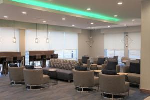 a waiting room with chairs and tables and a piano at La Quinta Inn & Suites by Wyndham Oxford in Oxford +41 photos