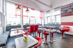 un restaurante con sillas rojas, mesas y ventanas en Hotel 108, en Hamburgo