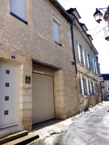 un bâtiment en pierre avec deux portes de garage dans une rue dans l'établissement Gite BR Al Buga, au Bugue