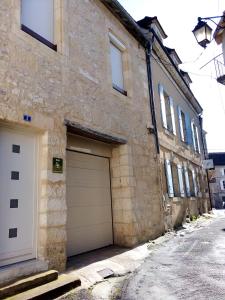 un edificio de piedra con dos puertas de garaje en una calle en Gite BR Al Buga, en Le Bugue