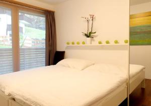 - une chambre avec un lit blanc et une fenêtre dans l'établissement Apartment Superior Parrot, à Zermatt