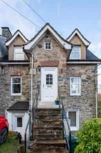 a stone house with a white door and stairs at 4 Still Brae in Tarbet