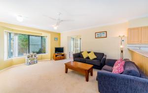 a living room with two couches and a tv at Oceania Cottage - LJHooker Yamba in Yamba