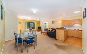 a kitchen and a living room with a glass table at Oceania Cottage - LJHooker Yamba in Yamba
