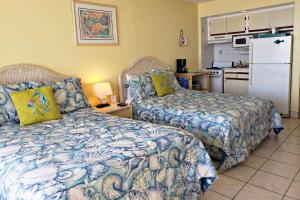 a bedroom with two beds and a kitchen with a refrigerator at Pirates Cove Condo Unit #227 in Daytona Beach Shores