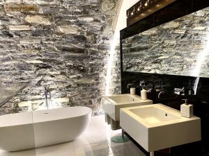 La salle de bains est pourvue de 2 lavabos blancs et d'un mur en pierre. dans l'établissement Villa Bianca, à Côme 122 autres photos
