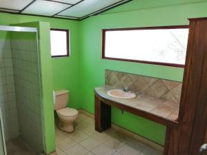 a green bathroom with a toilet and a sink at Hotel Marielos in Tamarindo