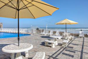 デイトナ・ビーチ・ショアーズにあるPirates Cove Condo Unit #715のプールの横のテーブルと傘