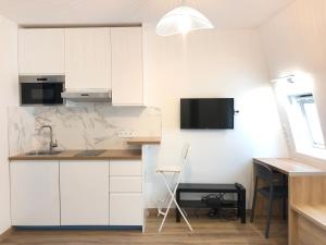 a kitchen with white cabinets and a desk at Studio neuf et cosy au centre de Paris in Paris