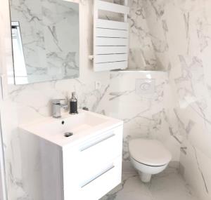 a white bathroom with a toilet and a sink at Studio neuf et cosy au centre de Paris in Paris