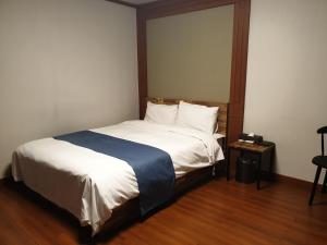 1 dormitorio con 1 cama con sábanas blancas y manta azul en The Beauty Hotel en Gangneung