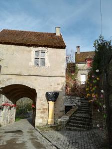 a stone building with an archway and a building with stairs at The Good Studio Vezelay in Vézelay
