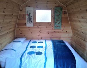 uma cama num chalé de madeira com uma janela em Rum Bridge 'Hazels' Pet Friendly Glamping Pod em Clare