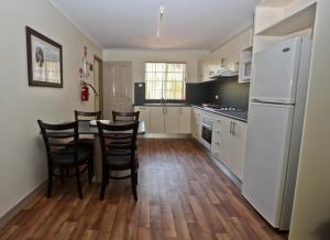 eine Küche mit einem Tisch und Stühlen sowie einem weißen Kühlschrank in der Unterkunft Alice On Todd Apartments in Alice Springs