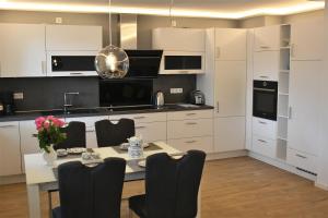 a kitchen with white cabinets and a table with chairs at Heykens Golfhuus Eagle in Wiesmoor