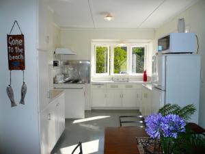 a white kitchen with a table and a refrigerator at Ridge Cottage - Oneroa Holiday Home in Oneroa