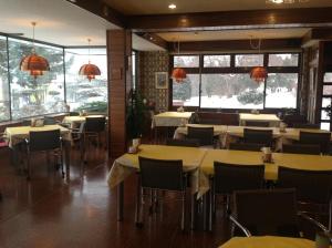ein Restaurant mit Tischen und Stühlen und großen Fenstern in der Unterkunft Pension Ohno in Sobetsu