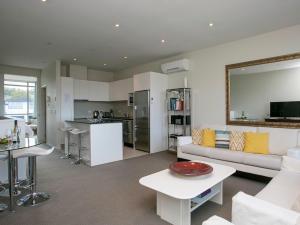 a living room with a white couch and a kitchen at Marinaside Villa - Taupo Holiday Apartment in Taupo