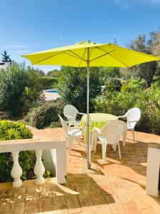 a yellow umbrella over a table and chairs at Casas do Ramalhete in Luz