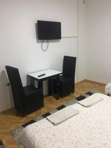 Pokój z biurkiem, 2 krzesłami i telewizorem w obiekcie Majestic Rooms&Apartments w mieście Prilep